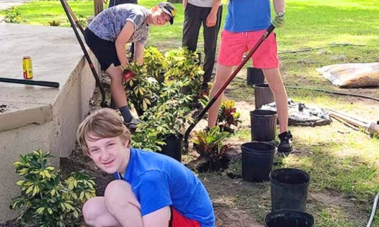 Teenage boys plant shrubs around a gazebo.