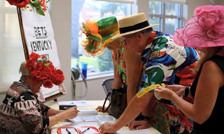 Attendees with tickets and derby hats at the betting table