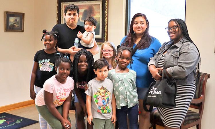 A mixed-race group of 6 girls and 3 adult chaperones small and pose for the camera.