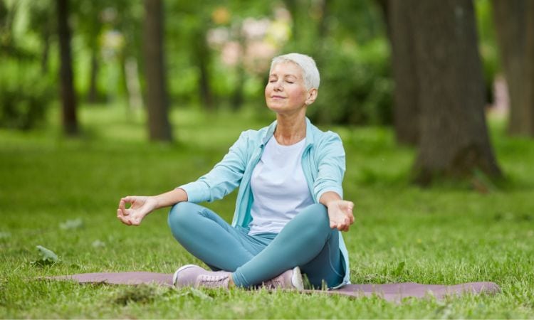Older woman meditates outdoors in yoga pose